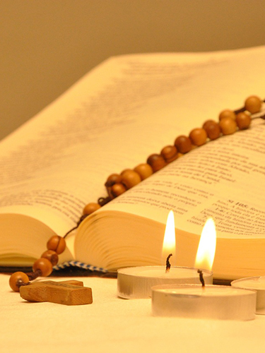 Bibel mit Rosenkranz und Kerzen